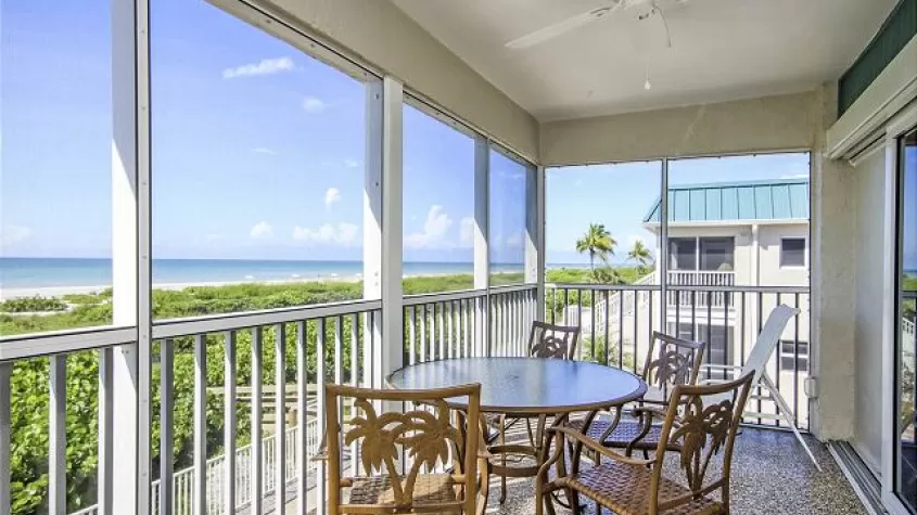 Screened in lanai with patio table and chairs at Sanibel Arms West Condos